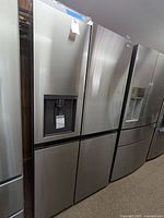 Front view of stainless steel LG side-by-side refrigerator alongside other units