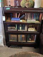Front view of entire bookcase showing three glass-front shelves and top surface with decorative items.