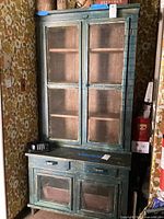 Front view of two-piece rustic wooden cupboard showing upper glass cabinet and lower section with drawers and doors