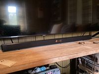 Full view of the Samsung sound bar placed on wooden surface showing length and design.