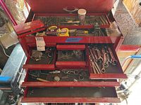 View of red tool chest organizing the different hand tools and accessories including drill bits, wrenches, tape measure, and Allen keys.