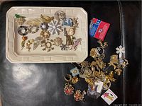 Full view of pins on a white tray and additional pieces scattered on black surface.