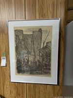 Framed pencil drawing hanging on wood paneled wall, showing full artwork and frame.