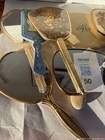 Photo showing various hand mirrors including faux leather textured and gold framed mirrors along with blue plastic handled mirror