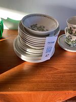 Stack of plates and bowls showing green floral design on white ceramic