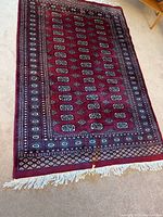 Top view of red area rug showing overall geometric pattern and white fringe