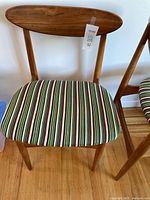 Front view of one teak chair showing curved backrest and striped seat