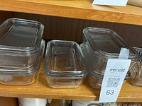 Set of five glass butter dishes with ribbed design and matching lids arranged on wooden shelves.