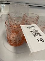 Four pink hobnail textured drinking glasses grouped together on a surface.