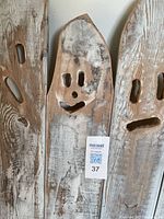 Close-up of a carved whitewashed wooden plank with a ghost face cutout painted in rustic style