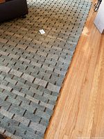 Large rectangular handwoven rug laid out on hardwood floor, showing overall pattern and condition.