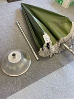 Folded green canopy, separated pole sections, and round base on floor