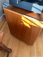 Side angle view of teak veneer finish on TV stand showing wood grain and polished surface.
