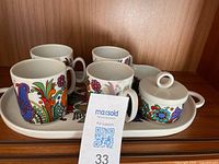 Full view of tray holding four mugs, sugar bowl and creamer