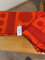 Folded orange and red drape fabric with circular and rectangular dot pattern on a table.