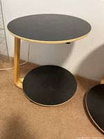 Side view of one black and natural wood IKEA end table on wheels showing adjustable top tray