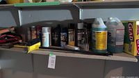 Shelf with multiple automotive products including sprays, wipes, fluids and a box of Glad storage bags.