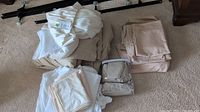 Overview of several folded bed linens including beige, white, and packaged linens.