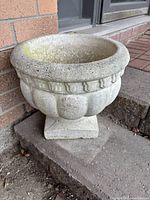 Heavy gray cement planter with vertical fluted details and thick rounded rim, weathered surface