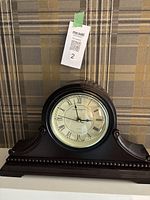 Front view of dark wood quartz mantle clock showing overall design and shape with clock face centered.