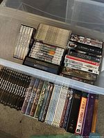 Overview of several DVD sets in clear storage box, showing titles including Downton Abbey, Rumpole of the Bailey, The Tudors, Robin Hood, Godfather, Black Adder, Winds of War.