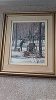 Full view of framed oil painting showing woodcutter chopping wood near wood stove in snow-covered forest.