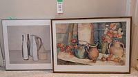 Two framed decorative prints displayed side-by-side on the floor against a wall, showing the still life images clearly.