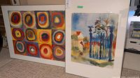 Both framed watercolor prints side by side showing one abstract colorful circular design and one fence scene.