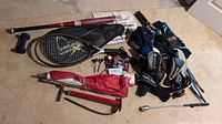 Wide view of all sporting items including golf club protectors, baseball bat, tennis racquet, umbrellas, hats, darts, headlamps, and flag