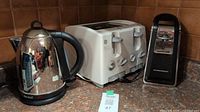 Wide shot showing the toaster, kettle and can opener on the kitchen counter.