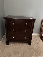 Front full view of nightstand showing three drawers and silver ring pulls