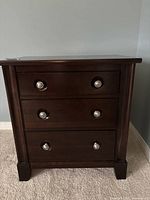 Front view of nightstand showing all three drawers and silver ring pulls