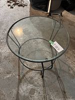 Full view of the round table showing the clear glass top and black metal frame
