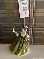 Front view of the Royal Doulton Simone figurine showing the woman in an olive green dress holding a hand mirror.