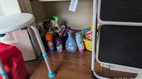 Adjustable shower stool with partially visible cleaning products and step ladder in kitchen corner