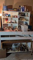Full view of workbench with shelves loaded with assorted tools and hardware, lower shelf contains hand tools and plastic bags of fasteners.