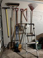 Photo showing the full set of garden and garage tools including shovel, rakes, brooms, dustpan, and Werner ladder