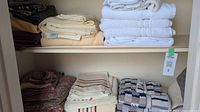 Top shelf with folded towels in white, cream, and beige colors.