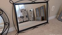 Mirror leaning against wall with other frames around it, showing overall size and style.