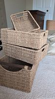 Stack of four wicker baskets showing three smaller baskets with cut-out handles and largest basket with wooden handles placed at the bottom