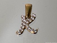 Front view of the letter K pendant showing pave-set diamonds on yellow gold.