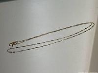 Full view of delicate alternating white and yellow gold chain necklace with lobster clasp