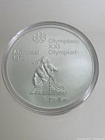 Front side of silver coin with Indigenous athlete and Olympics emblem.