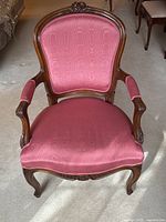 Front view of antique Louis XV style armchair showing raspberry pink taffeta upholstery and carved wood frame.