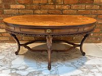 Full front view of oval coffee table showing wood veneer top pattern, apron and carved legs