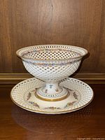 Front view of compote on underplate showing overall shape and decoration