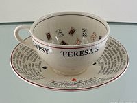 Cup on saucer showing exterior text ‘Gypsy Teresa’s’ and playing card motifs inside cup