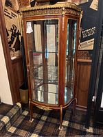 Full frontal view of the kingwood vitrine display cabinet showing glass front, curved sides, ormolu mounts and three interior glass shelves.