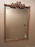Full front view of rectangular gilt frame mirror hanging on wall