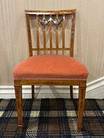 Full front view of chair showing wooden frame, painted decoration and upholstered seat